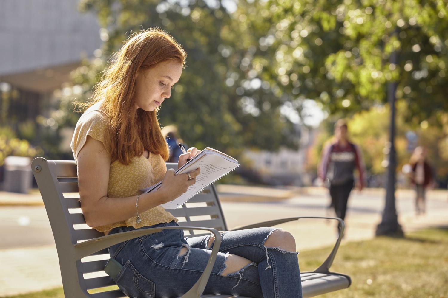 一位<a href='http://7f.nexpvc.com/'>bv伟德ios下载</a>学院的学生在校园里的长椅上读书.